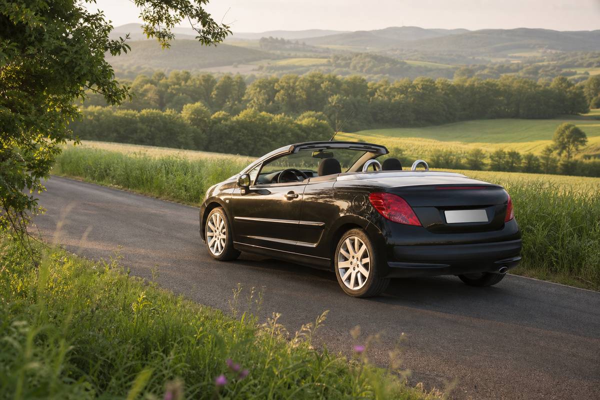 Vue large d une Peugeot 207 CC toit ouvert sur une route de campagne verdoyante